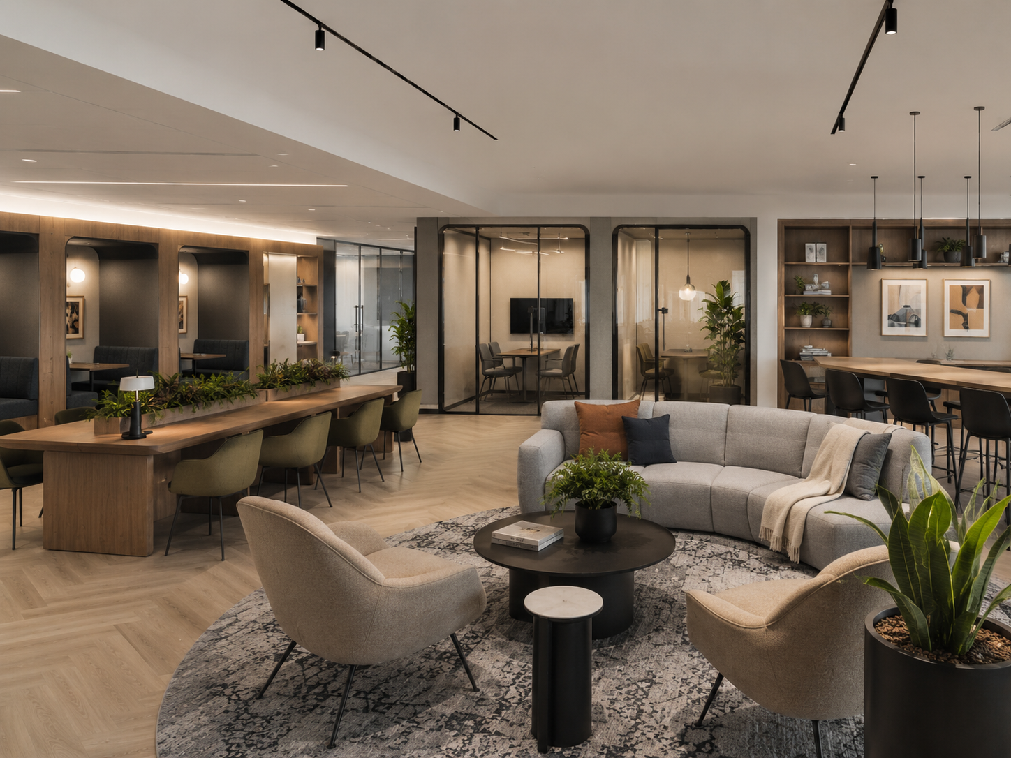 Premium office lounge with sofa seating, lounge chairs, long work tables, plants, and glass meeting rooms